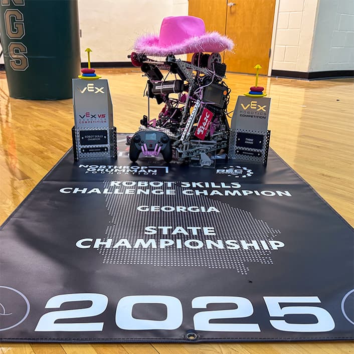 3142C's VEX V5 robot between its 2025 Georgia State Robot Skills Champion and Think Award trophies
